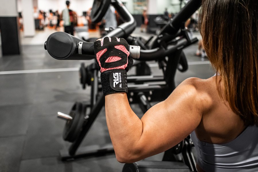 chica fitness con guantes haciendo espalda
